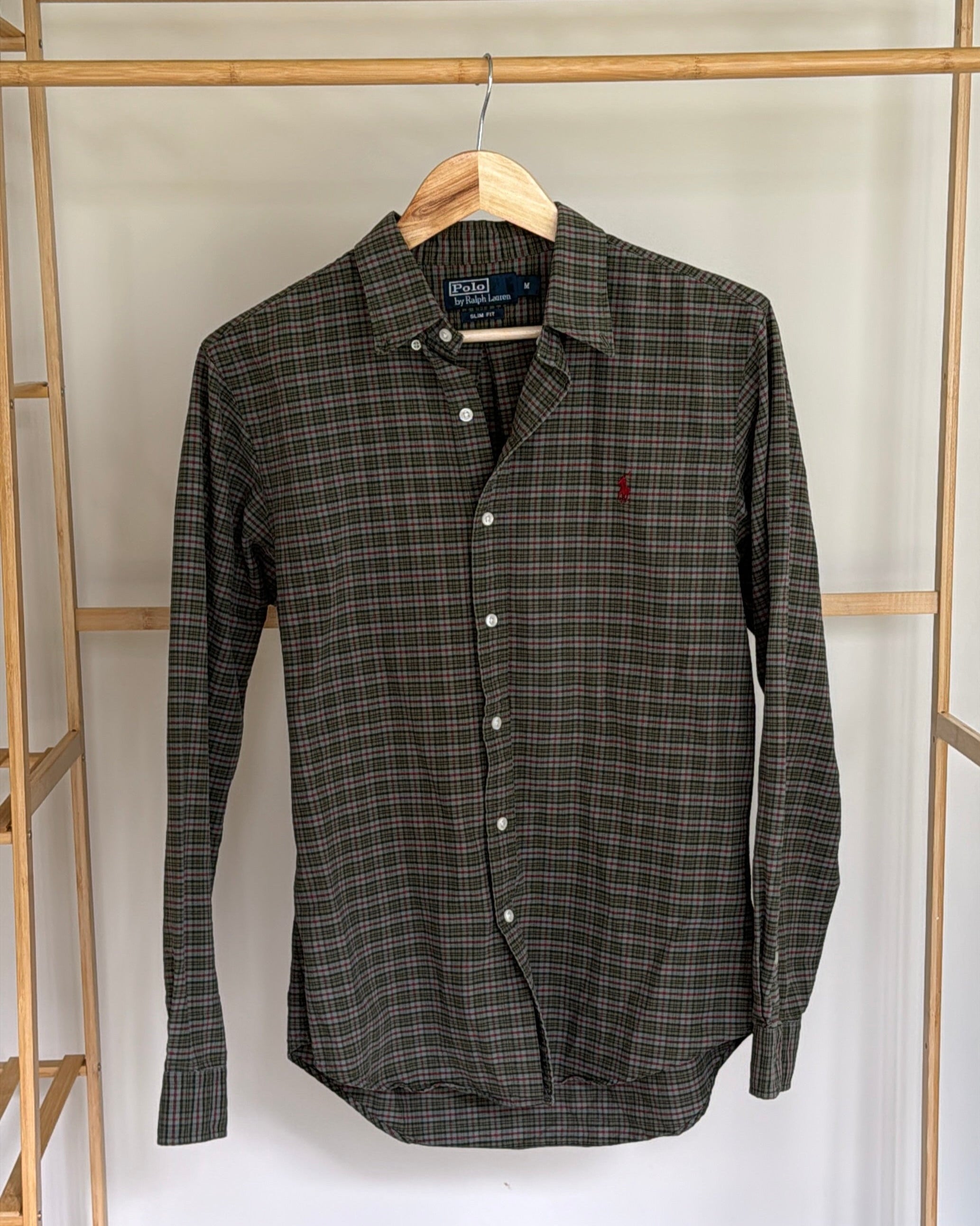 Plaid shirt hanging on a wooden rack against a white wall