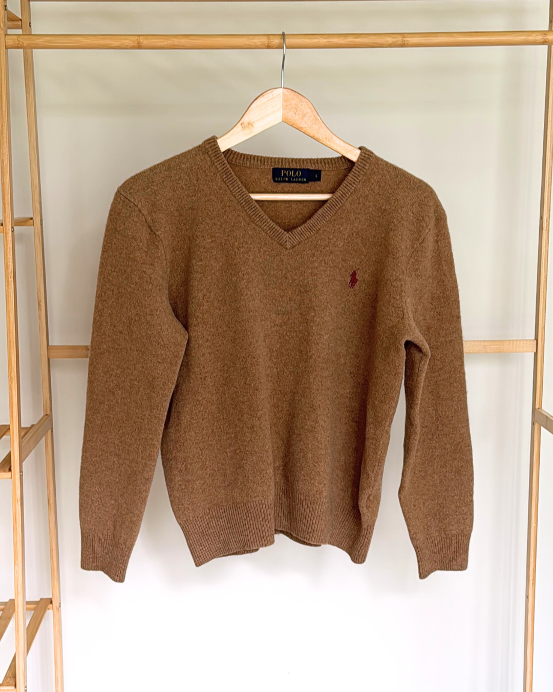 Brown sweater with Ralph Lauren logo on a wooden rack.